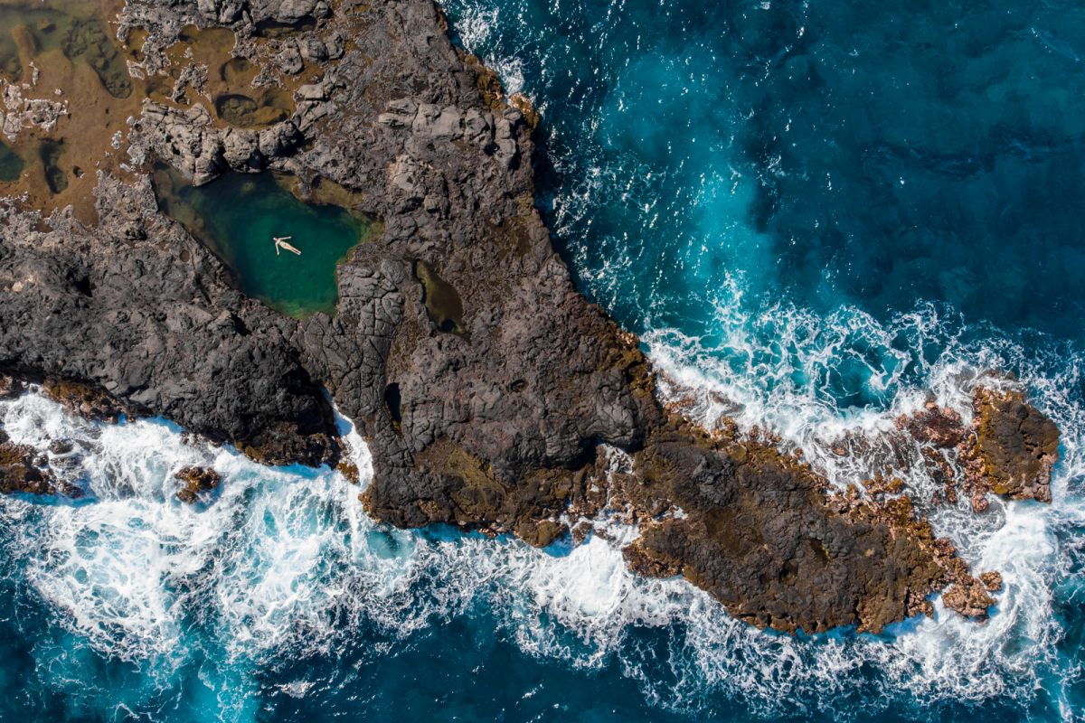 Aerial of a model swimming in a natural ocean pool in Maui Hawaii