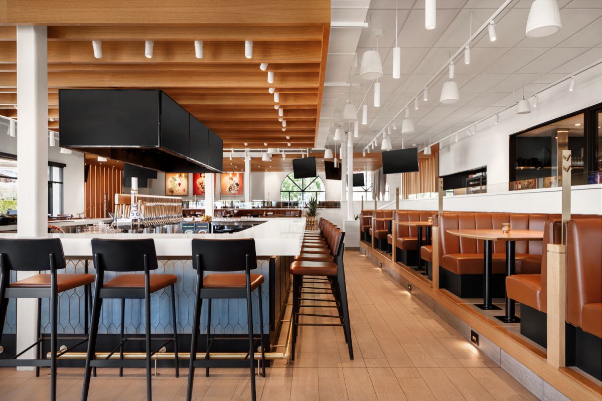 King Taps Kelowna restaurant bar during daylight looking across bar stools and benches