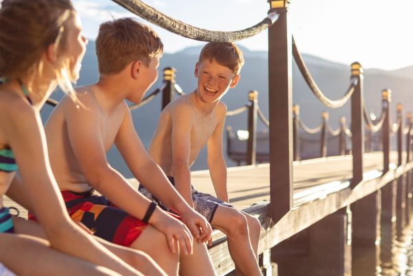 Kids sitting on a dock backlit laughing
