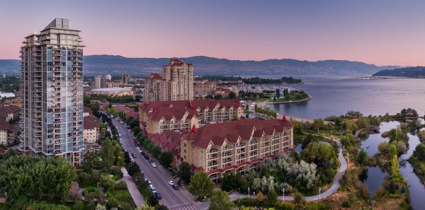Drone aerial of downtown Kelowna BC at sunset with urban setting and Okanagan Lake and the bridge in the distance