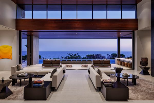 Inside of a Malibu mansion looking through the living room to the ocean view at sunset