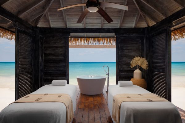 Luxurious spa and massage room at Sandals Royal Caribbean in Jamaica with view out to the ocean and two massage beds with a large soaker tub